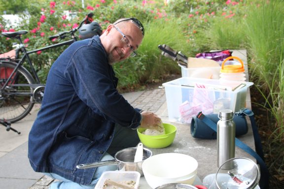 Ein Mann in blauer Jacke knetet einen Brotteig in einer Schüssel